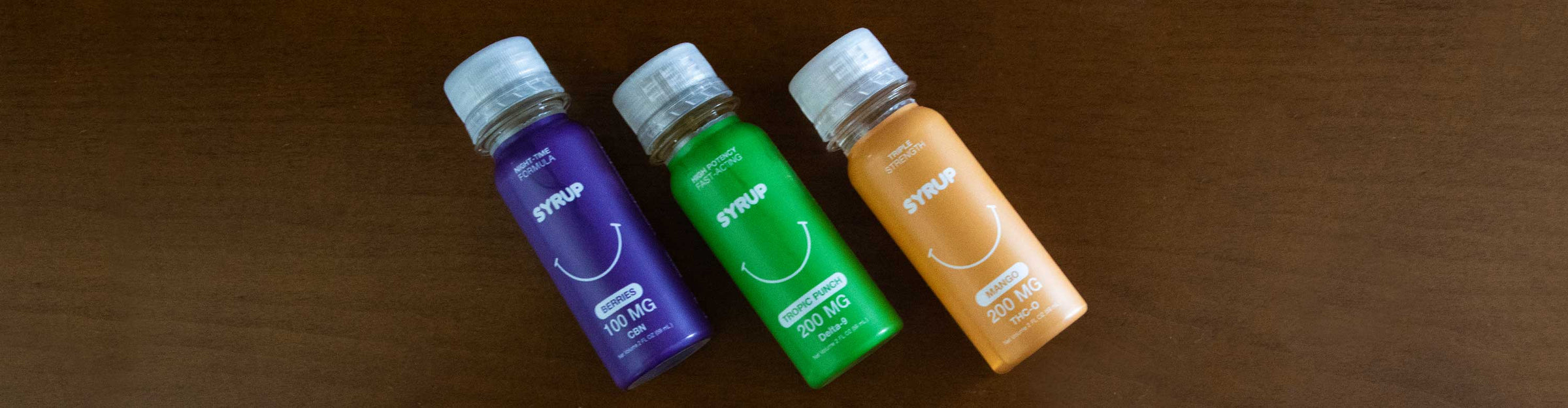 Sweet Life CBD Syrup flavors laying down on wooden table