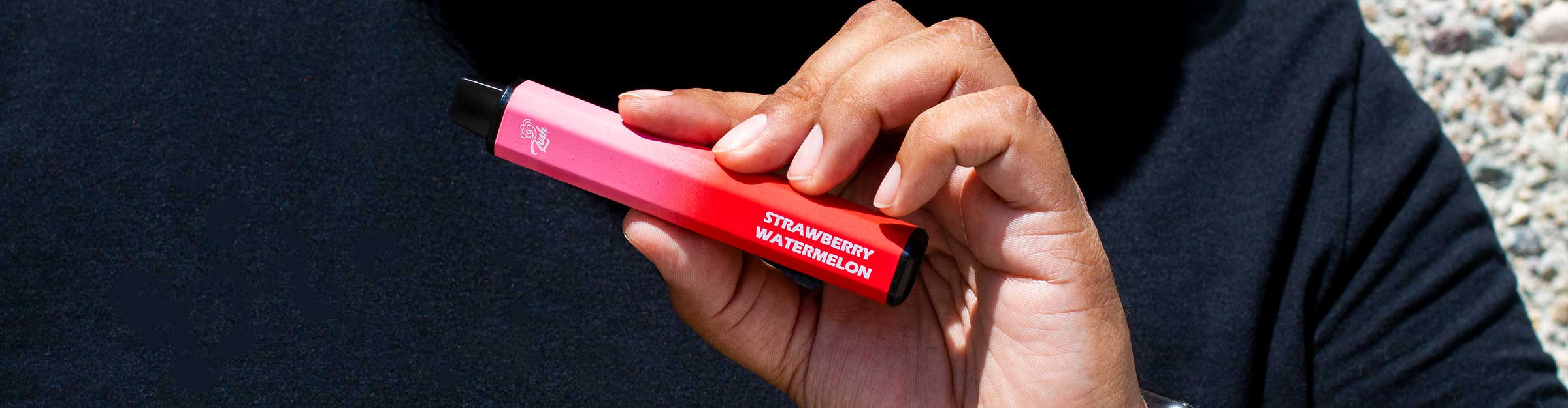 Man in black t-shirt holding the Crush Twosome Disposable Vape Pen outside near building